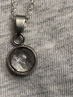 Close-up of meteorite pendant showing metallic fragment inside round bezel.
