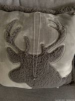 Silver chain necklace laid out fully on a soft cushion with antler design.