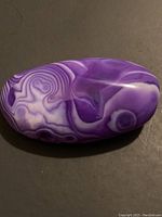 Top view of the polished purple agate stone showing white and purple banding patterns.