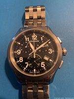 Front view of watch showing black dial, Arabic numerals, subdials and date window