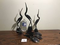 Overall view of the carved horn bird sculptures and spoons with a water bottle for scale.