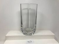 Front view of the clear rectangular crystal vase with thick bottom on a white display stand.