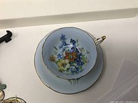 Top view of the cup showing floral pattern and gold trim on sky blue background.