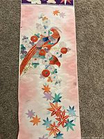 Pink fabric panel featuring a detailed bird perched on stylized flowers and maple leaves, with cloud-like background patterns.