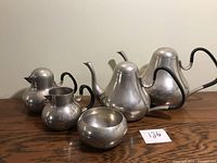 Front view of the full pewter tea and coffee set showing all six pieces arranged on wooden surface.