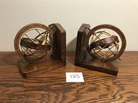 Pair of wooden bookends each with an antique brass armillary sphere globe on a wooden base.