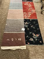 Photo showing the first large roll of silk fabric with various color blocks and embroidered traditional Japanese designs on black, red, and other backgrounds.