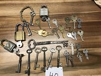 Top-down view of the entire key lot showing various keys arranged on a wooden surface, with two padlocks visible at the top left.