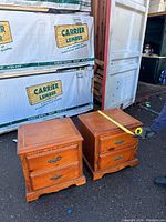 Photo showing two wooden bedside tables side by side with a tape measure indicating width of approximately 22 inches.
