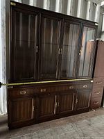 Front view of large wooden china cabinet with glass display doors, drawers, and lower storage doors, measured width