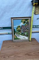 Frontal image showing the framed petit point picture with a measuring tape stretched alongside the frame height, measuring about 18 inches.