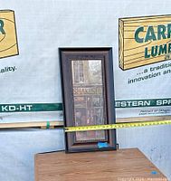 Front view of decorative framed artwork with tape measure showing width of approximately 13 inches.