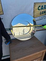 Round mirror being measured across the diameter, showing 24 inch size.