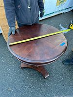 Photo of round wooden table showing diameter measurement approximately 29 inches across the top surface.