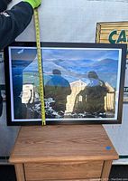 Framed photographic print of a coastal landscape being measured vertically showing approximately 38 inches in height.