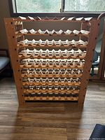 Front view of a wooden wine rack with zigzag slots for bottles, showing overall design and condition.