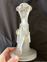 Full view of frosted glass nude lady candlestick with applied gold and purple decoration.