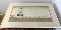 Framed watercolour artwork showing a bird on a railway crossing sign in a grassy field under overcast sky.