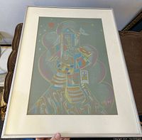 Framed abstract surreal pastel artwork depicting a colorful geometric structure on gray paper held upright, showing entire artwork and frame