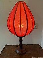 Close-up image of the lamp showing the red silk shade with wooden vertical striping and Tang-style wooden base.