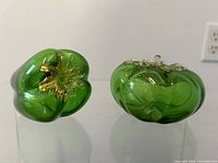 Front view of both green art glass bell peppers showing gold aventurine detail inside the glass.