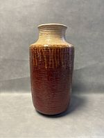 Front view of the pottery vase showing ribbed upper neck and textured brown lower body.
