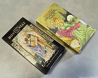 Photo of two boxes of tarot cards side by side on a gray surface, showing the front covers of Golden Botticelli Tarot and Golden Universal Tarot sets.