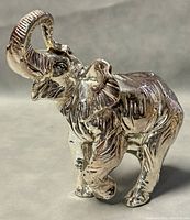 Front angle view of silver elephant statue showing raised trunk, detailed ears, and textured skin.