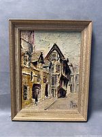Framed oil painting depicting a textured street scene with buildings, signed by Niala.