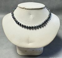 Front view of the dark baroque freshwater pearl choker necklace displayed on a stand.