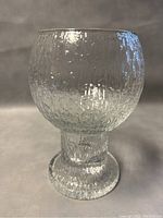 Front view of a clear textured crystal vase on a gray background