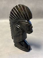 Front angle showing detailed carved headdress and facial features of Mayan/Aztec warrior paperweight made of polished black obsidian.