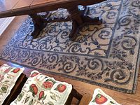 Jute area rug under a dark wooden dining table showing the pattern and wear on the surface.