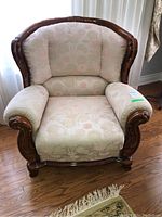 Front view of armchair showing floral upholstery and carved wood frame