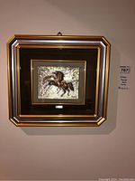 Overall view of framed metal relief hanging on wall