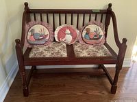 Wooden bench with floral upholstered seat cushions and round pillows with ducks and cat designs.