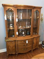 Front view of the wooden china cabinet with glass doors, showcasing the curved central glass door and diamond leaded glass side panels.