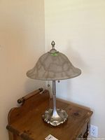 Full view of metallic finish table lamp with frosted glass shade showing overall shape and condition.