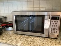 Full view of the GE microwave oven placed on countertop, showing stainless steel exterior and digital keypad.