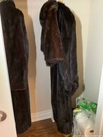 Two dark brown mink fur garments hanging on hooks side by side