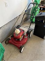 Red Craftsman lawnmower with Briggs and Stratton engine, showing side view with black handle and white wheels.