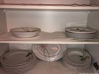 Top and middle shelves with stacked round plates and an oval platter with Water Lily design.
