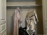 View of hanging valances and bedspread in closet with plastic garment covers.