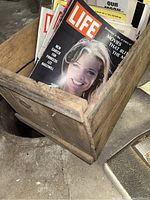 Wooden crate filled with Life magazines from 1960s and 1971 featuring various cover images including a smiling woman.