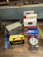 Overview of all items including rechargeable battery, dust masks, eye mask, respirator cartridges in boxes on a wooden surface