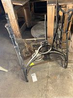 Photo showing cast iron table base and attached antique sewing table parts including metal lever and plate