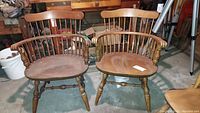 Photo of two wooden Windsor style arm chairs placed side by side showing entire chairs with wear and scratches visible