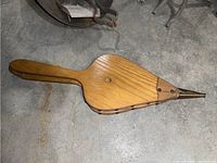 Wooden fireplace bellows front side showing wood grain and brass nozzle