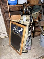 Corona Extra wooden-framed mirror leaning against shelf next to the golf bag.
