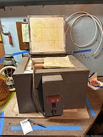 Full view of Roka Kiln Model T7 with open insulated firebrick-lined lid on metal body and control panel on front.